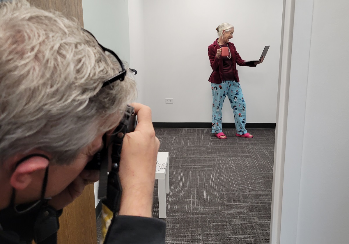 Brian behind the camera taking a photo of staff on a laptop in an empty office.