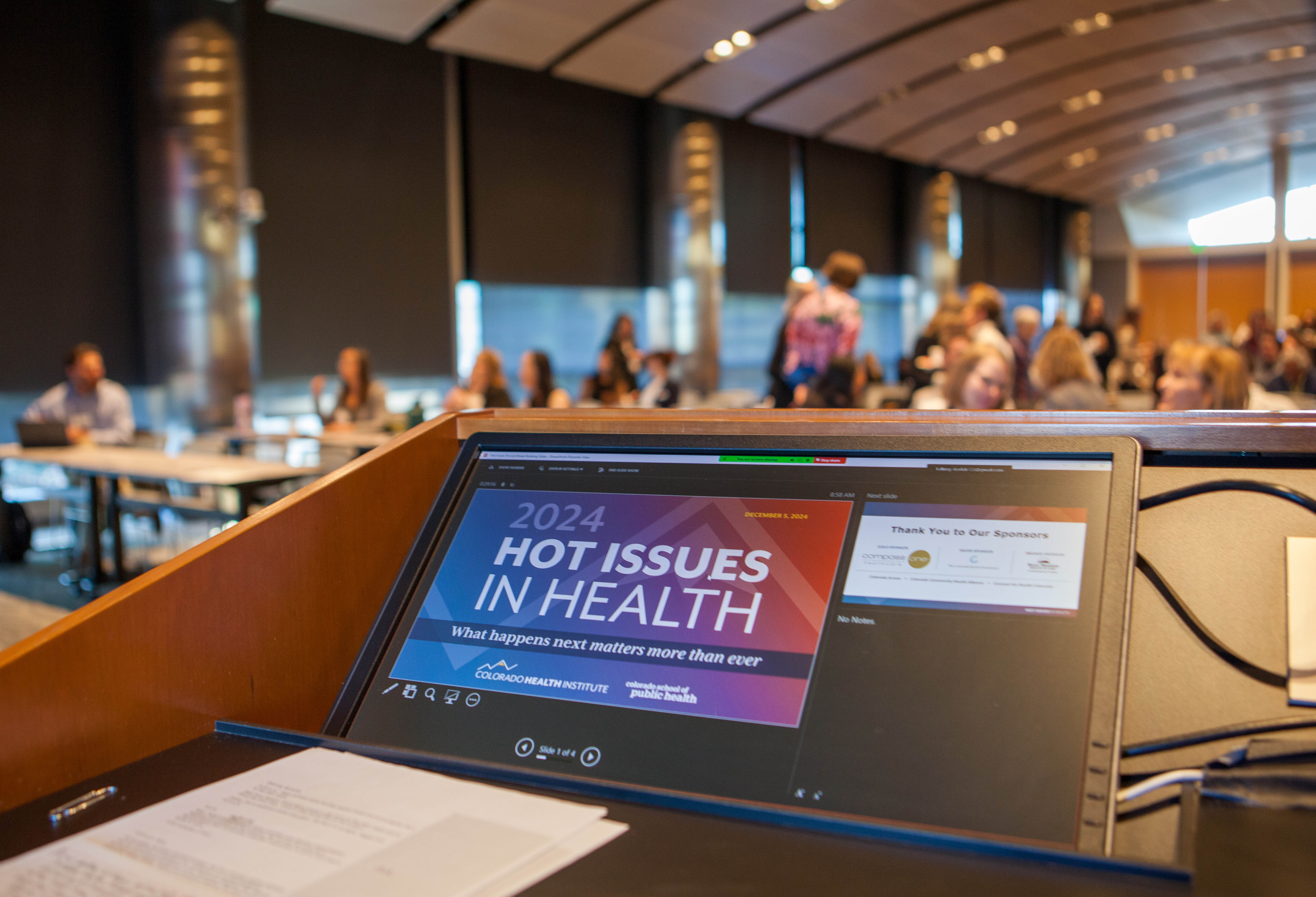 A computer on a podium showing the Hot Issues in Health logo