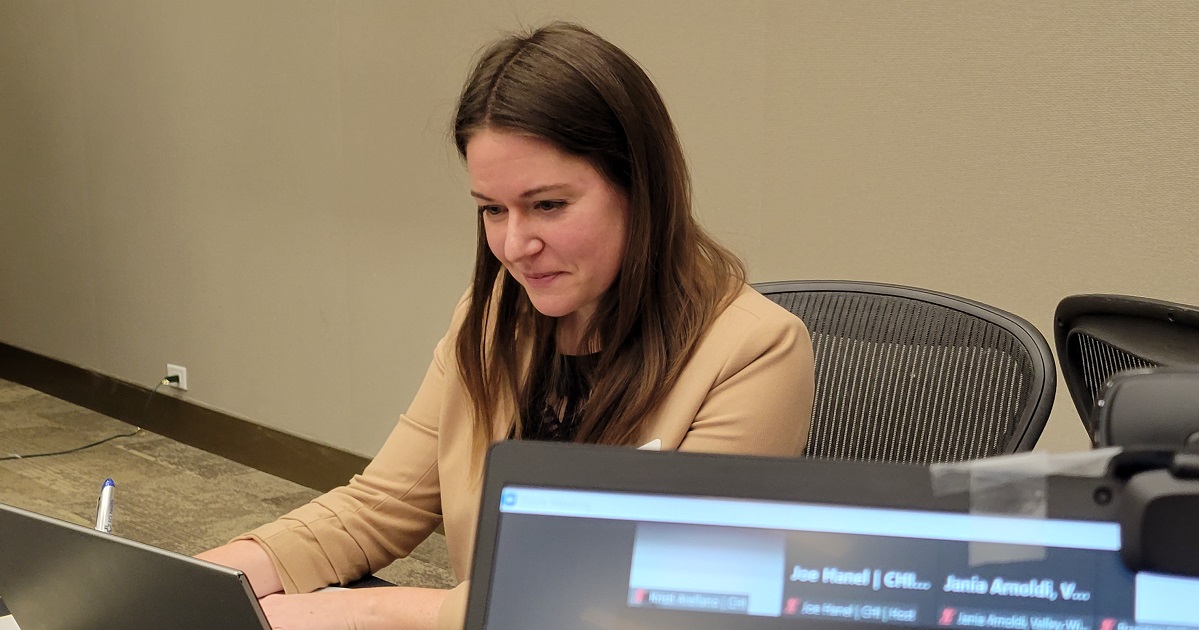 Nicole on a laptop interacts with virtual conference participants.