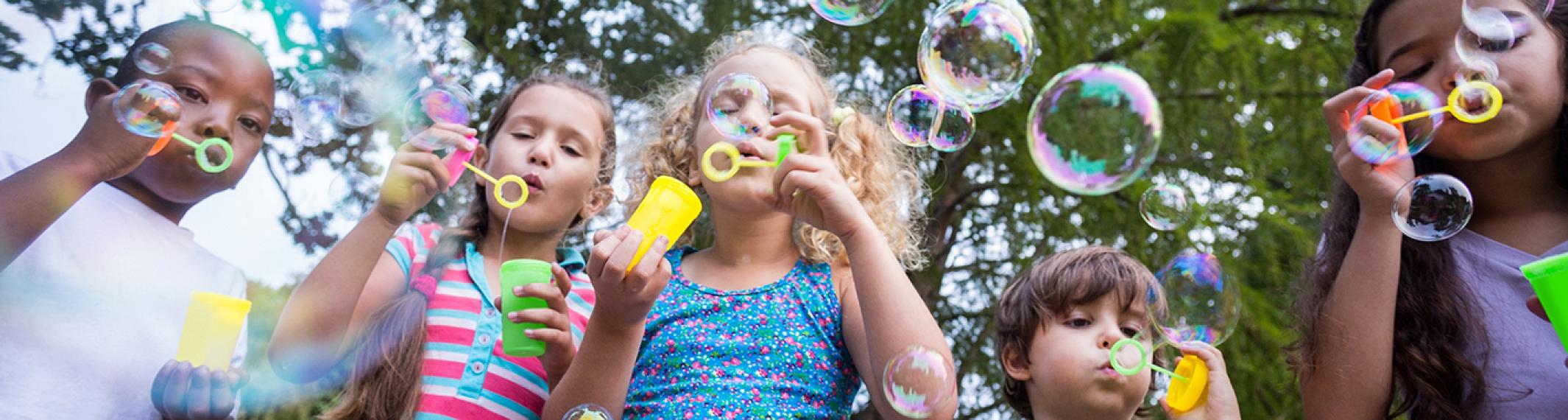 A group of young children blowing bubbles