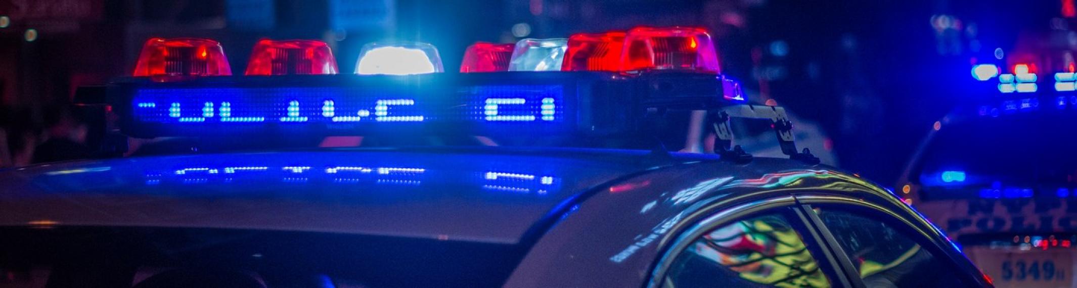 Picture of the top of a police car with red and blue lights flashing at night