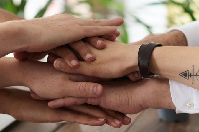 Closeup photo of people stacking their hands on each other's hands