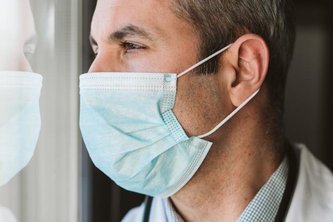 Closeup of a doctor wearing a mask looking out a window to the left