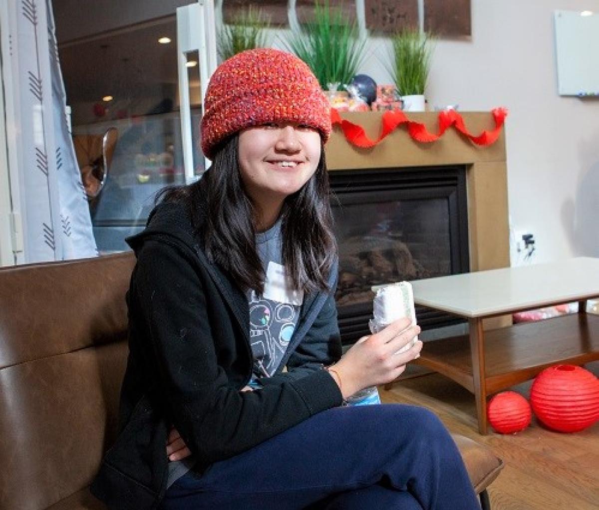 Girl sits in living room with a wrapped treat